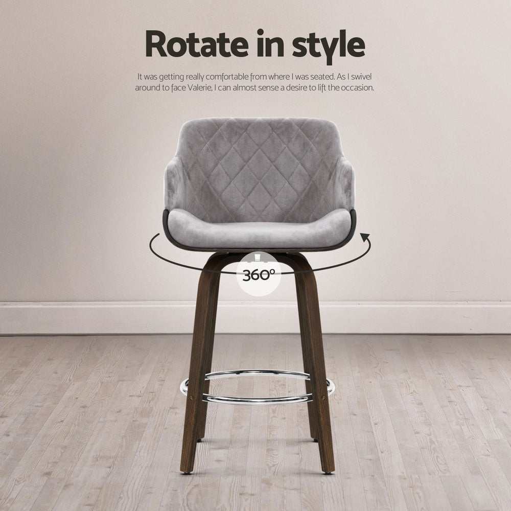 Velvet padded swivel bar stool with wooden legs and chrome footrest in grey, featuring 360-degree rotation and contoured backrest.