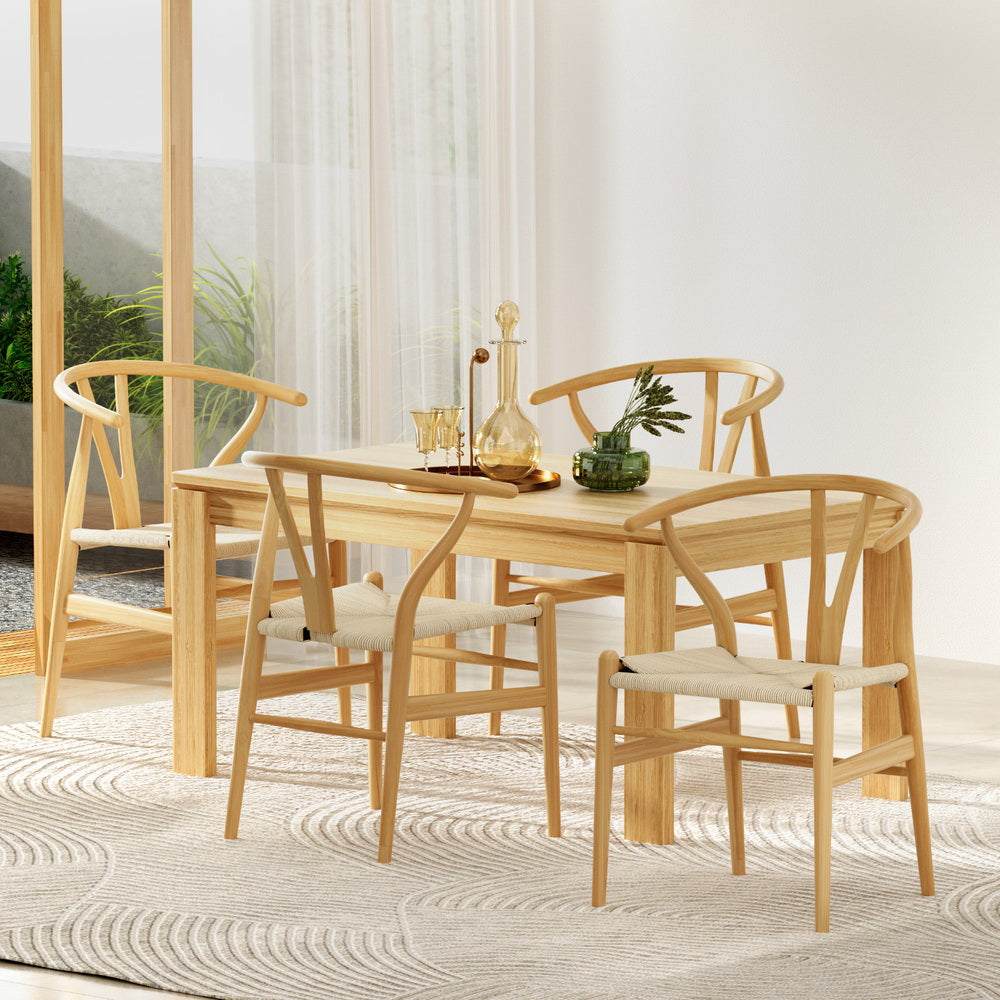 4 Artiss Wishbone Dining Chairs with Rattan Seats around Dining Table in Bright Room.