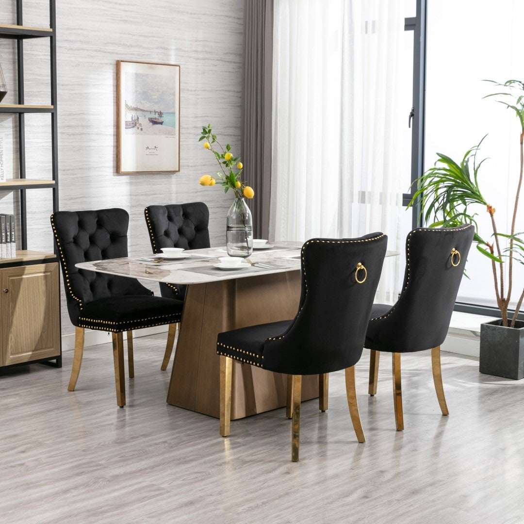 4x velvet dining chairs in black with button-tufted design, golden metal legs, and decorative studs in modern dining room.