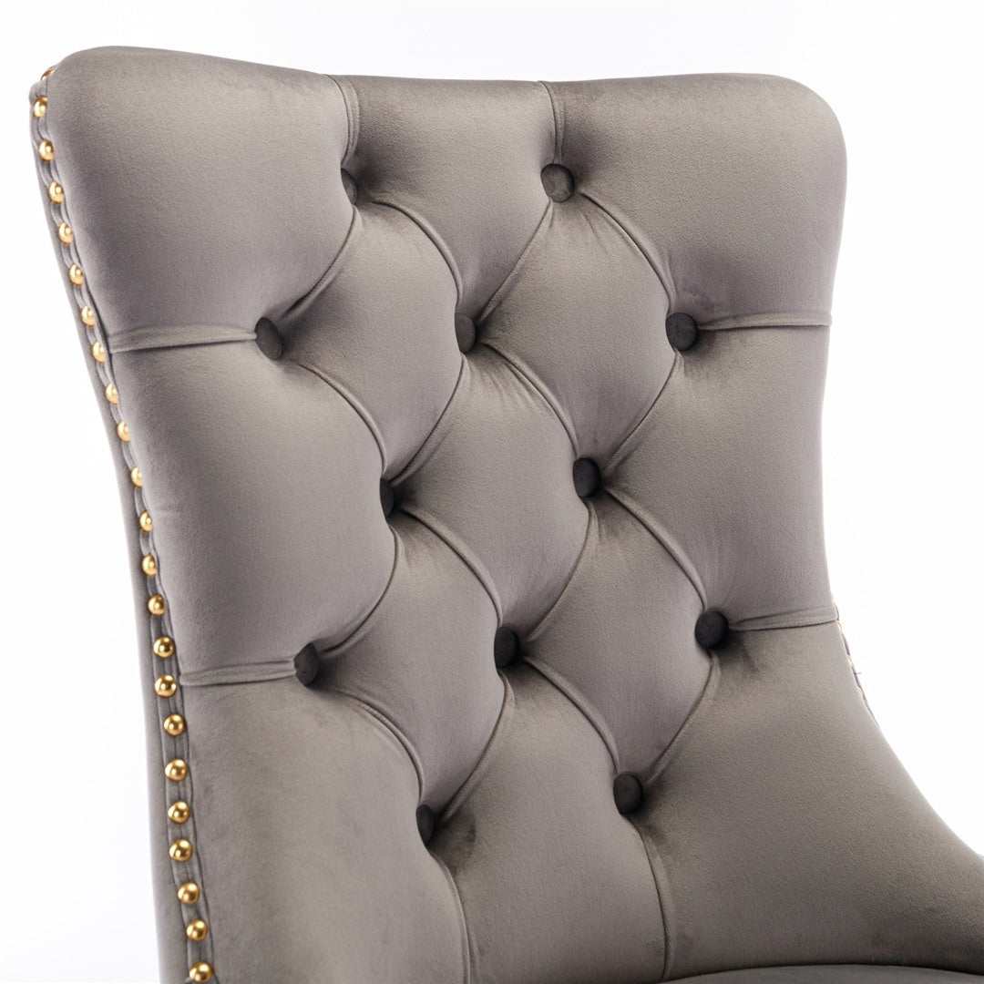 Grey velvet dining chairs with gold metal legs and button-tufted fabric.