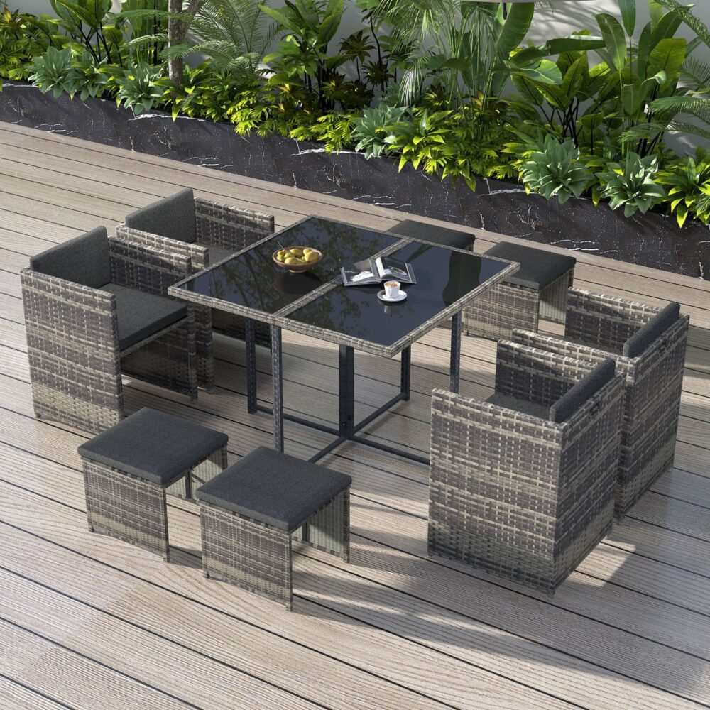 Horrocks 8 Seater Outdoor Dining Set in grey with rattan design, glass table top, armchairs, and ottomans on a patio setting.