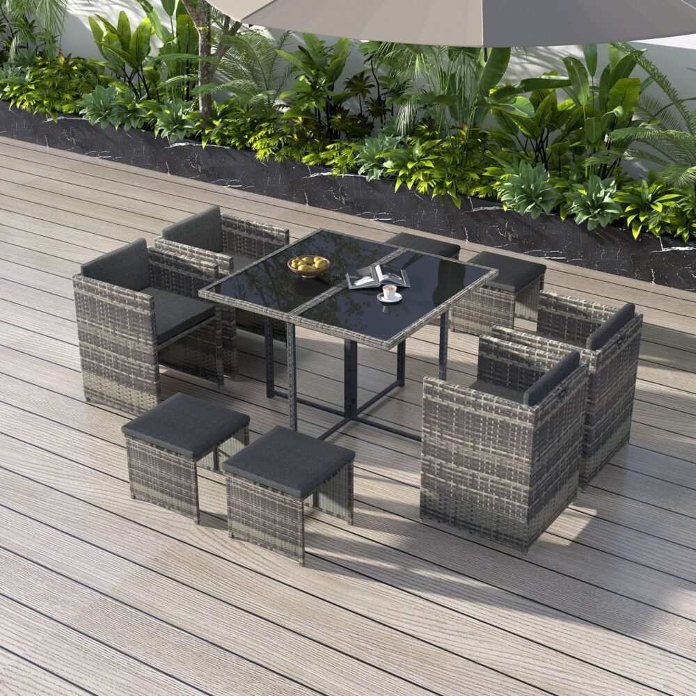 Horrocks 8 Seater Outdoor Dining Set in grey with rattan design, tempered glass table, armchairs, ottomans, and cushions on a patio.