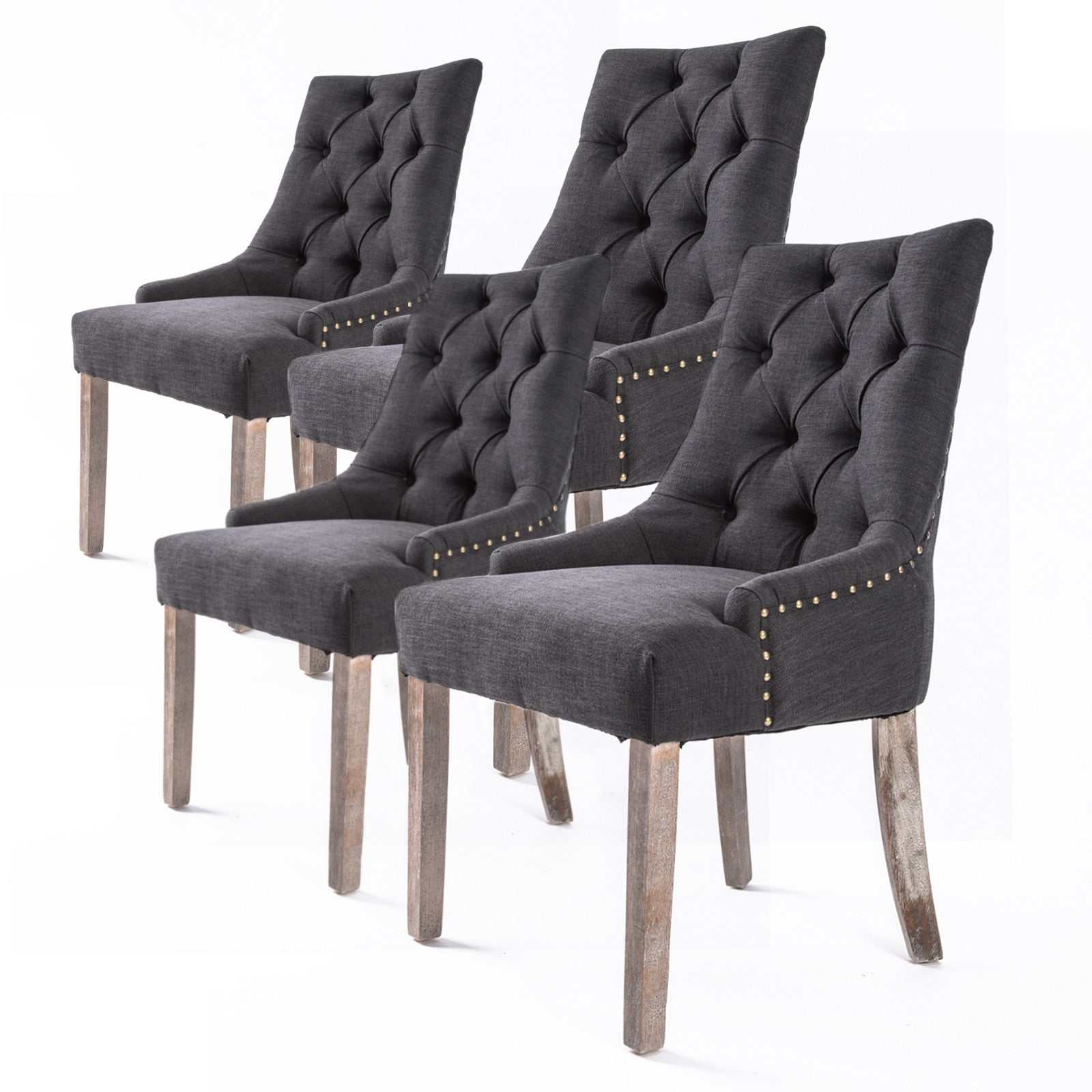 Set of four black French Provincial dining chairs with oak legs, brass studding, and deep tufted upholstery.
